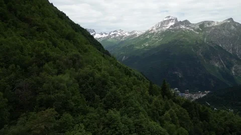 Flight over green mountain below view of mountain village Stock Footage 307878477