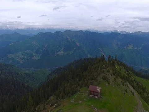 Flight over a green mountain range next to an abandoned village Video stock 80530395