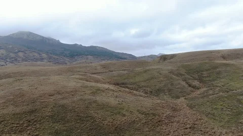 Flight over the hills with dry grass on a cloudy day mountains Stock-Footage 105670142