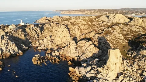 Flight over huge sea cliffs with lighthouse and small bay Stock Footage 128841950