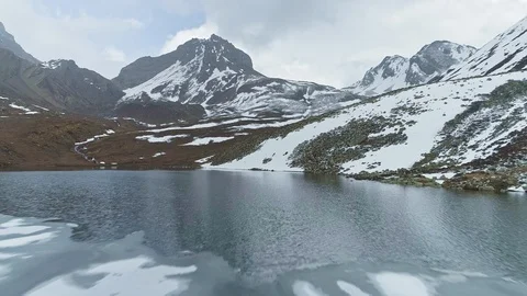 Flight over ice floe on highland lake, reflections of snow peaks on water, Nepal Stock Footage 124680972