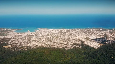 Flight over the island forest,  distant port city and the blue ocean Stock Footage 101758543
