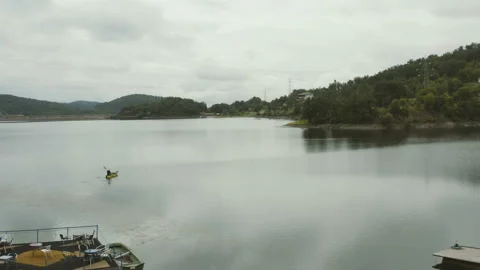 Flight over a large lake with a man kayaking over the lake Stock Footage 136047023