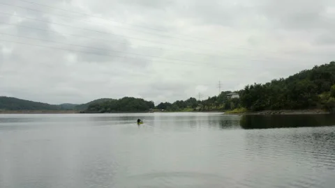 Flight over a large lake with a man kayaking over the lake Stock Footage 136119482