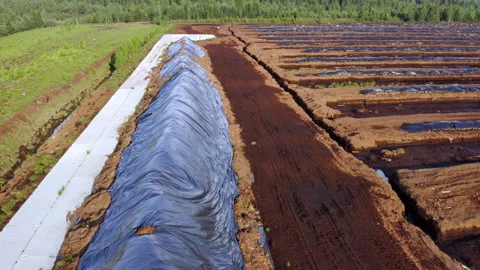 Flight over a large peat pile covered with polyethylene film. Video stock 317934996