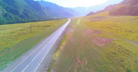 Flight over mountain asphalt highway road and meadow Stock Footage 119890817
