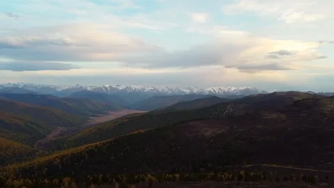 Flight over the mountain peaks. Panoramic view of mountains and clouds at sunset Stock Footage 142418172