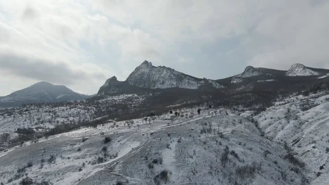 Flight over a mountain range in the snow on a cloudy day Stock Footage 104910415