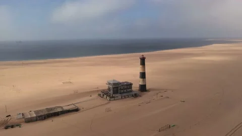 Flight over the oceanfront lighthouse at Sandwich Harbour Stock Footage 157583870