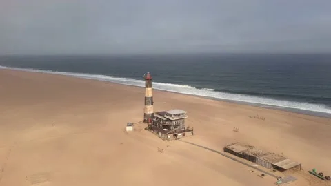 Flight over the oceanfront lighthouse at Sandwich Harbour Stock Footage 157923019
