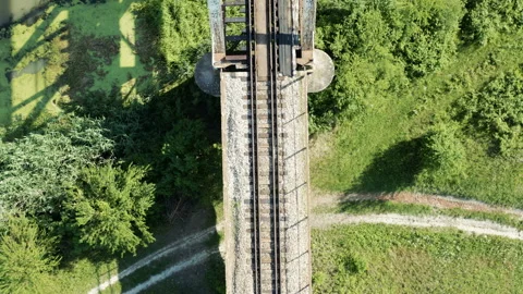 Flight over an old railway bridge over a murky river Stock Footage 133154376