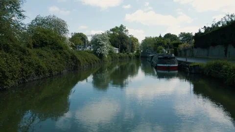 Flight over over a canal and boat calm waters green banks and sunny day Stock Footage 296821836