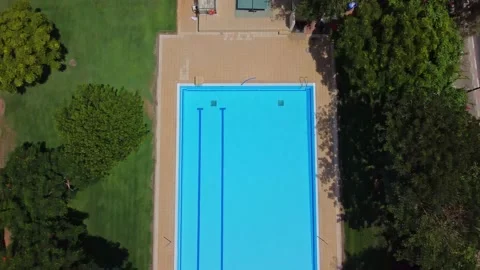 Flight over the pool.Aerial view pool without people surrounded by green trees Stock Footage 165170744