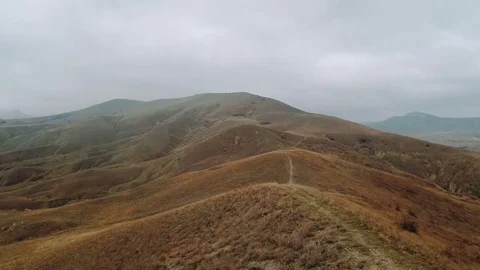 Flight over the ridge of a hill with a footpath Stock Footage 84552067