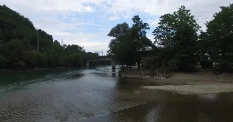 Flight over a river to a bridge when a train is passing Stock Footage 53895049
