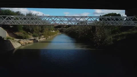 Flight over a river in a city, drone passes under a bridge and a road, the bi Stock Footage 220881552