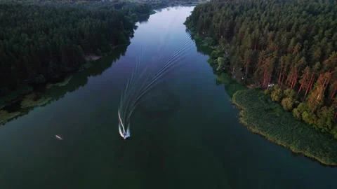 Flight over a river in the morning with small motor boat passing underneath Stock Footage 205616094