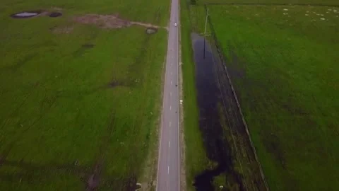 Flight over the road along which the car is driving in a field near the mountain Stock Footage 159539100