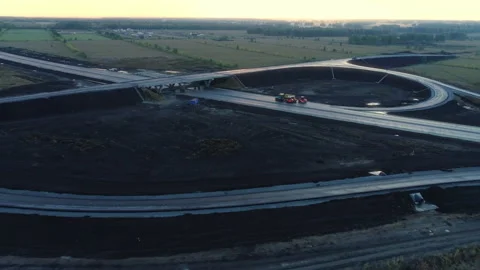 Flight over a road junction under construction at sunset. Road vehicles are Stock-Footage 137952353