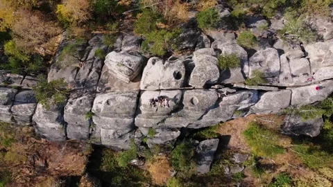Flight over the rocks in the autumn forest. Sitting people on a mountain, a big Stockbeeldmateriaal 243258883