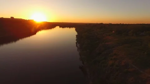Flight over the rocky coast of a large river next to a city during sunset Video stock 89380713