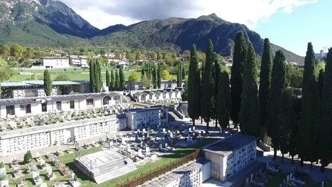 Flight over a small cemetery with Alps in the background 스톡 동영상 76568422
