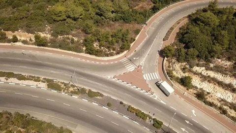 Flight over a small curved freeway with lone cars, a bridge, green trees around Stock Footage 119311947