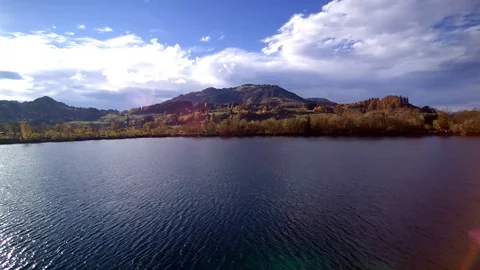 Flight over a small lake in front of a mountain panorama Stock Footage