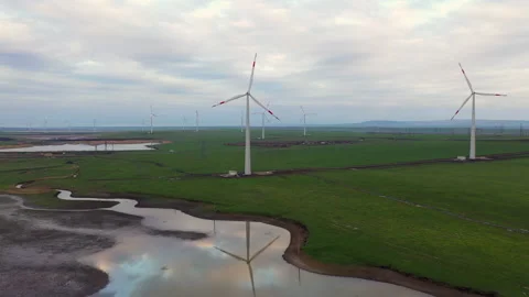 A flight over a small lake which reflects the windmills set around. Video stock 229768693