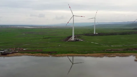 A flight over a small lake which reflects the windmills set around. Stock Footage 230239222