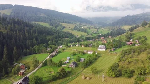 Flight over a small village located among the green mountains Stock Footage 212364413