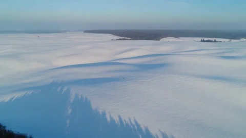 Flight over snow-covered fields. Long shadows of hills. Man travels alone. Stock-Footage 147692662