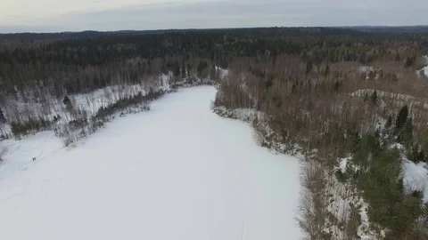 Flight over snow-covered lake with frozen water towards forest Stock Footage 92856046