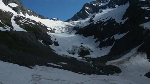 Flight over snowy cliffs below top in spring Stock Footage 305512677
