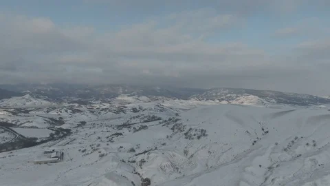 Flight over the snowy slopes of a hill Stock Footage 105680977