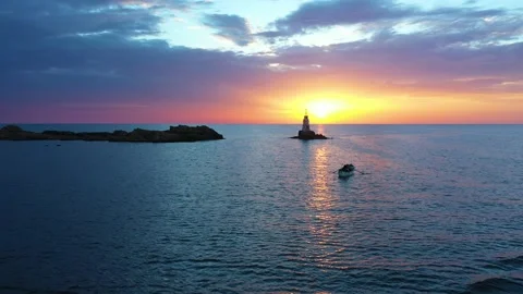 Flight over a sunny path to a lighthouse on an island and a beautiful sunrise Stock Footage 176479739