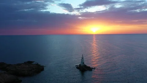 Flight over a sunny path to a lighthouse on an island and a beautiful sunrise Stock Footage 252852629