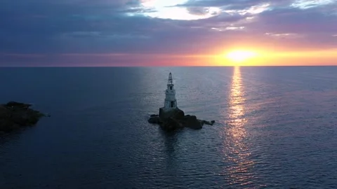 Flight over a sunny path to a lighthouse on an island and a beautiful sunrise Stock Footage 253509020