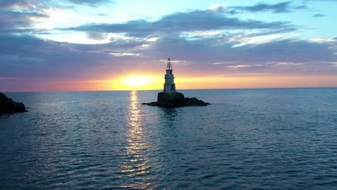 Flight over a sunny path to a lighthouse on an island and a beautiful sunrise Stock Footage 269139741