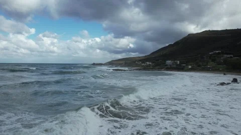 Flight over surf toward a rocky coast under dramatic clouds, Crete Stock Footage 346723930