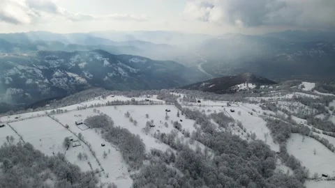 Flight over the top of the snow-covered mountain on which the country houses are Stock Footage 147620991