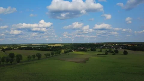 Flight over wind turbines, in rural surroundings, with fields and blue skies Stock Footage 345658847