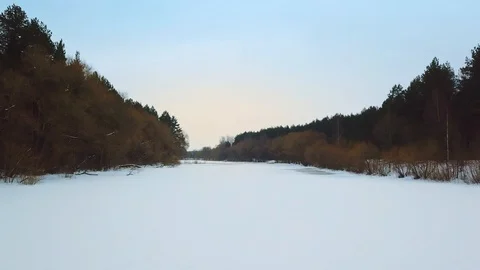 Flight over the winter river. Camera is flying over frozen river in the middle Stock Footage 90131375