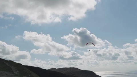 Flight of a red paraglider against the background of blue sky, clouds and Video stock 320597776