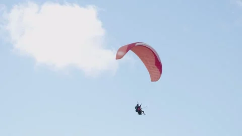 Flight of a red paraglider against the background of blue sky and clouds Vidéo 320598691