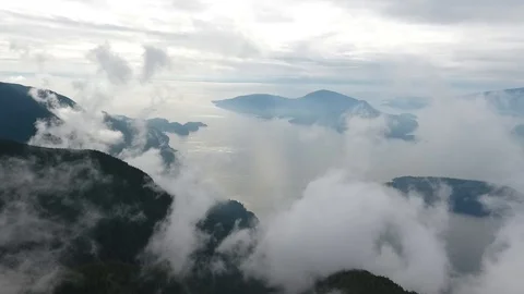 Flight through clouds overlooking mountain and ocean Vídeo Stock 90680145