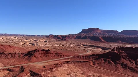 Flight Towards Ancient Red Rock Buttes and a Winding Desert Path in Utah 4K Stock Footage 331084863