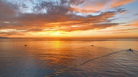 Flight traverses dramatic sunrise over Costa del Sol's calm waters, as two Vidéo 318283009