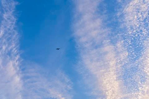 Flight of a twin-engine plane high in the sky against a blue sky Stock Photos