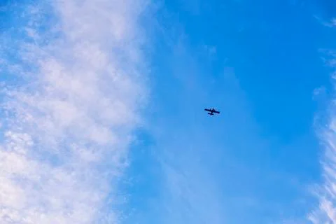 Flight of a twin-engine plane high in the sky against a blue sky Stock Photos